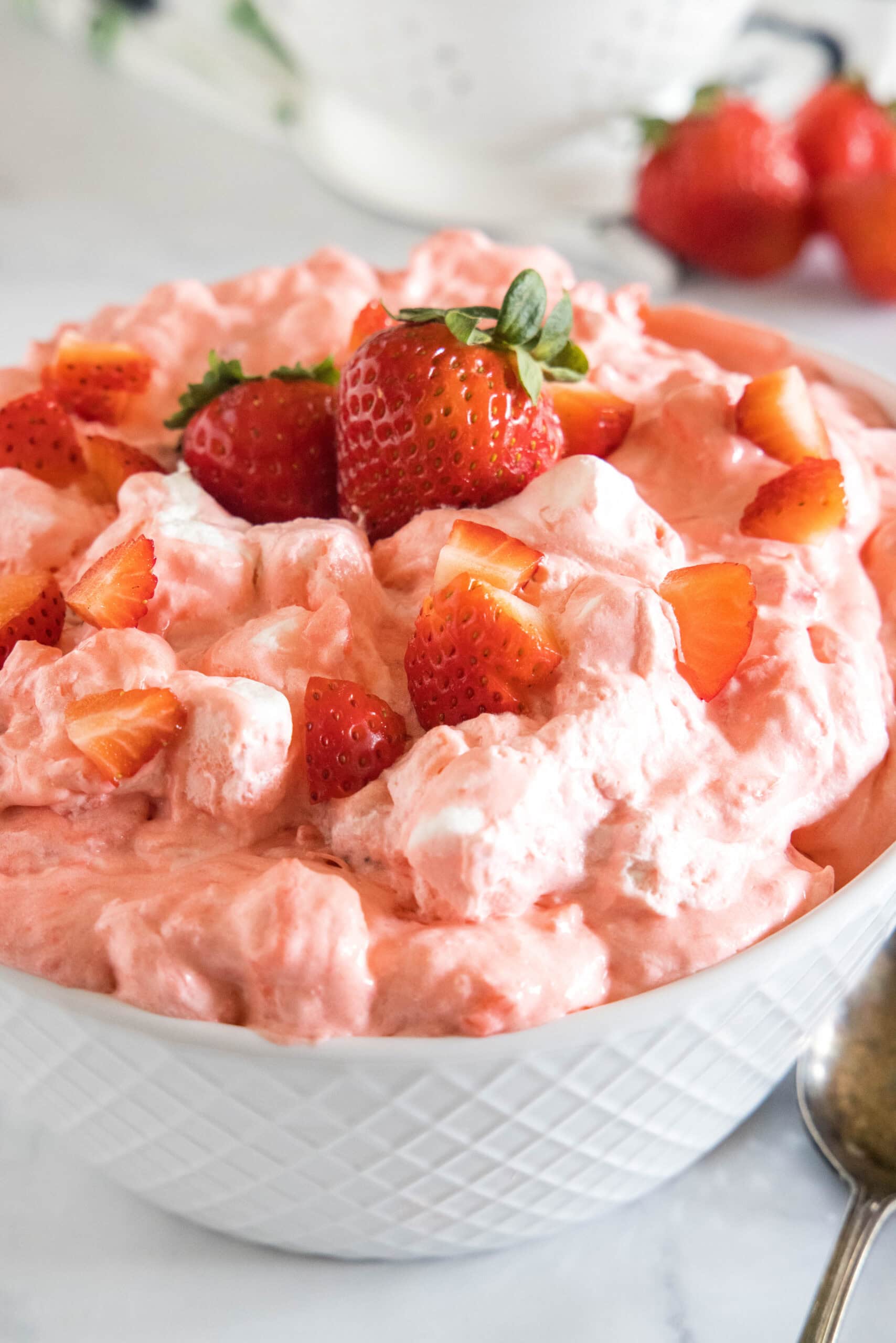 Strawberry fluff topped with chopped strawberries in a white bowl.