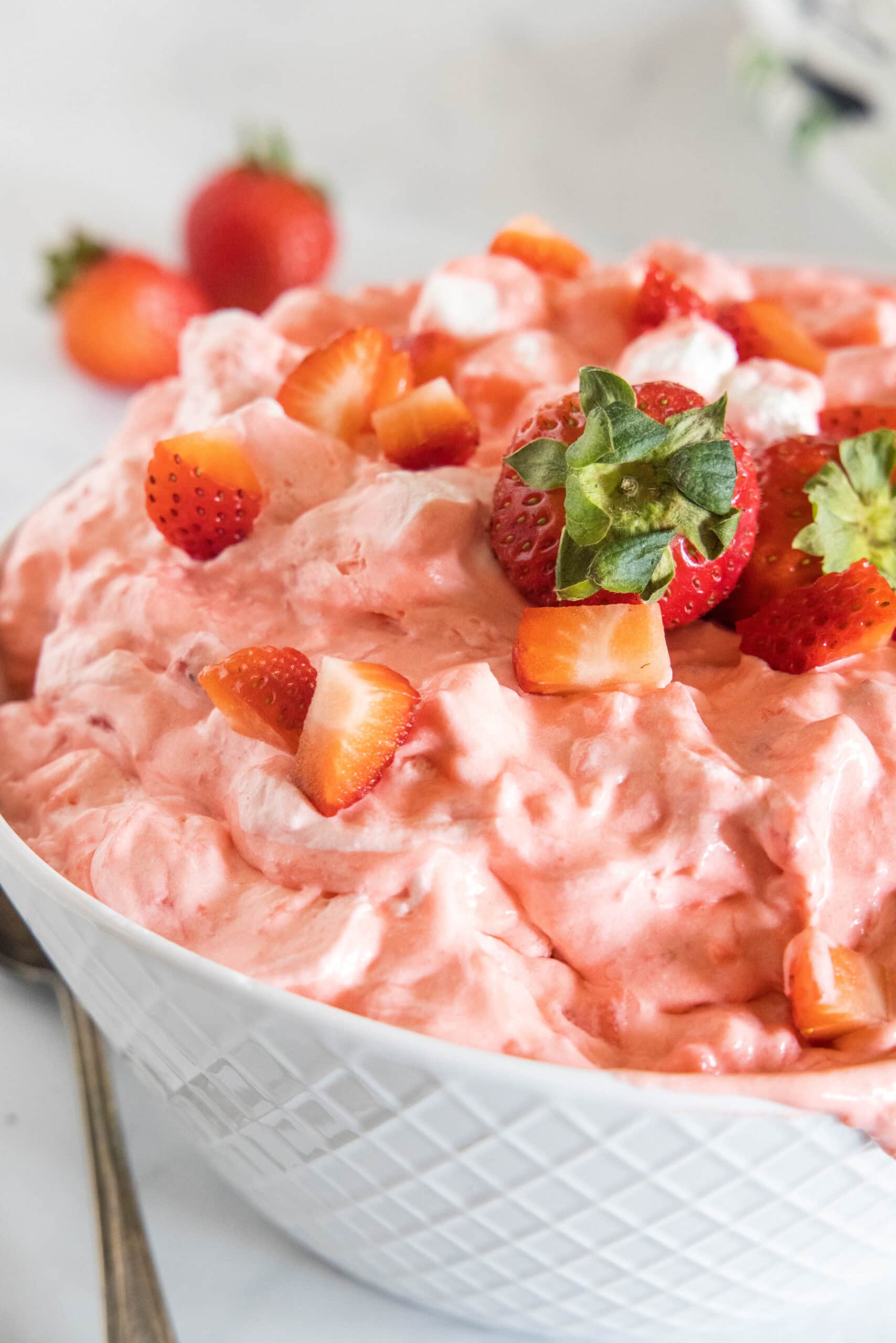 Strawberry fluff topped with chopped strawberries in a white bowl.