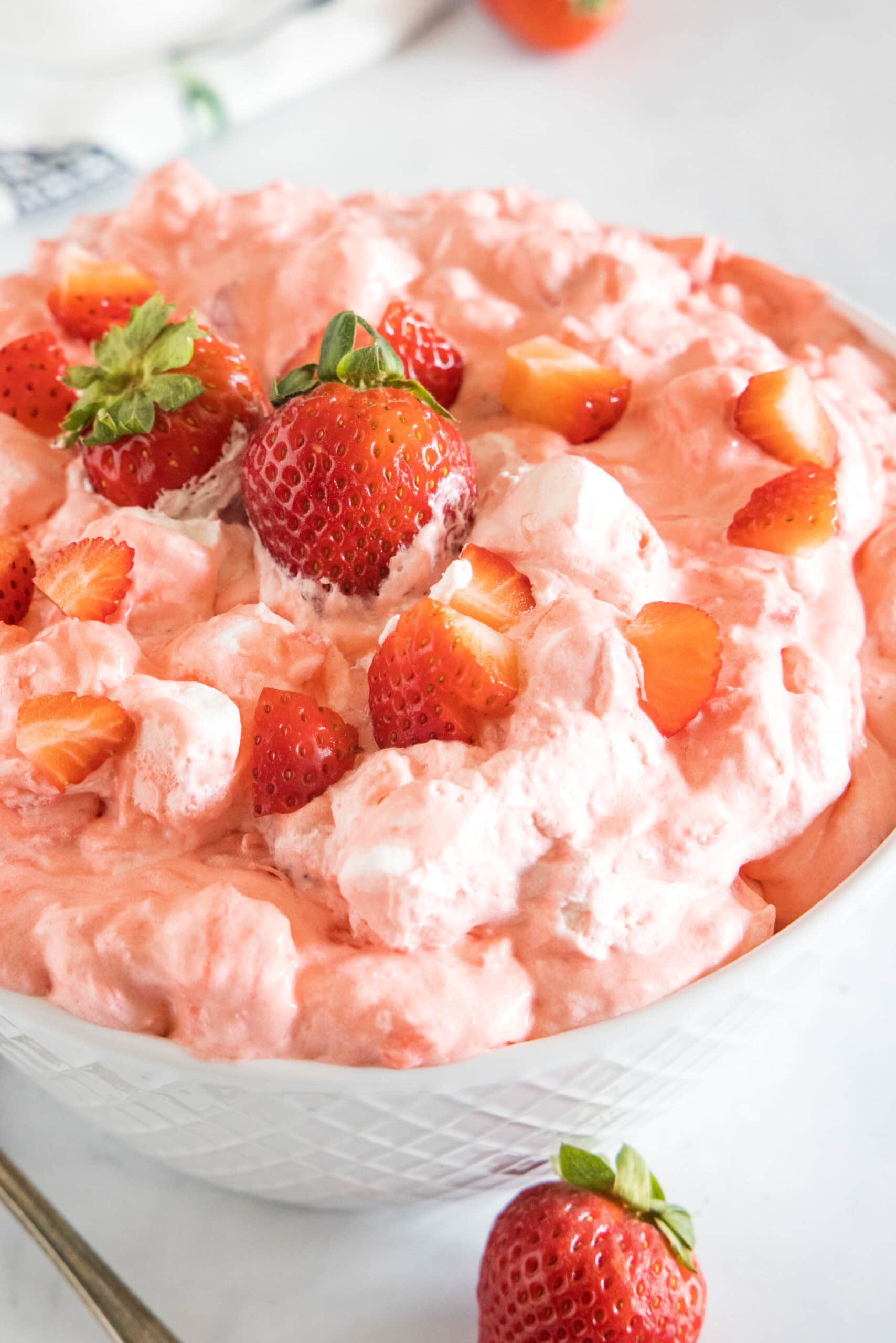 Strawberry fluff topped with chopped strawberries in a white bowl.