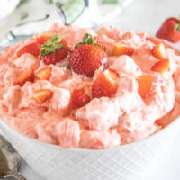Strawberry fluff topped with chopped strawberries in a white bowl.