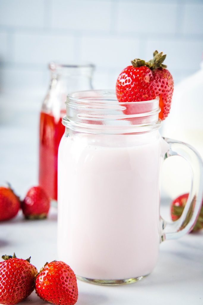 cup of strawberry milk with strawberry on rim of glass