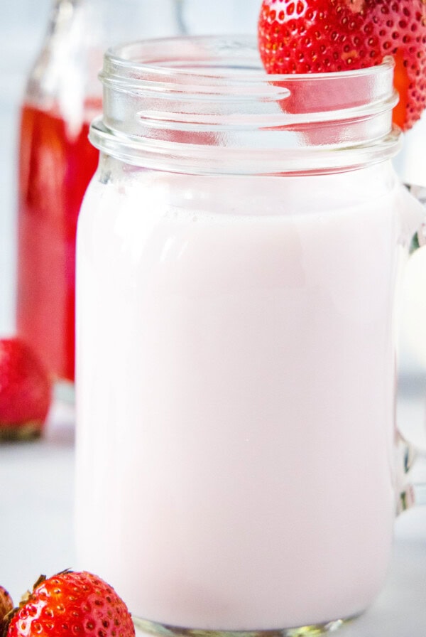 close up of strawberry milk with strawberry on rim of glass