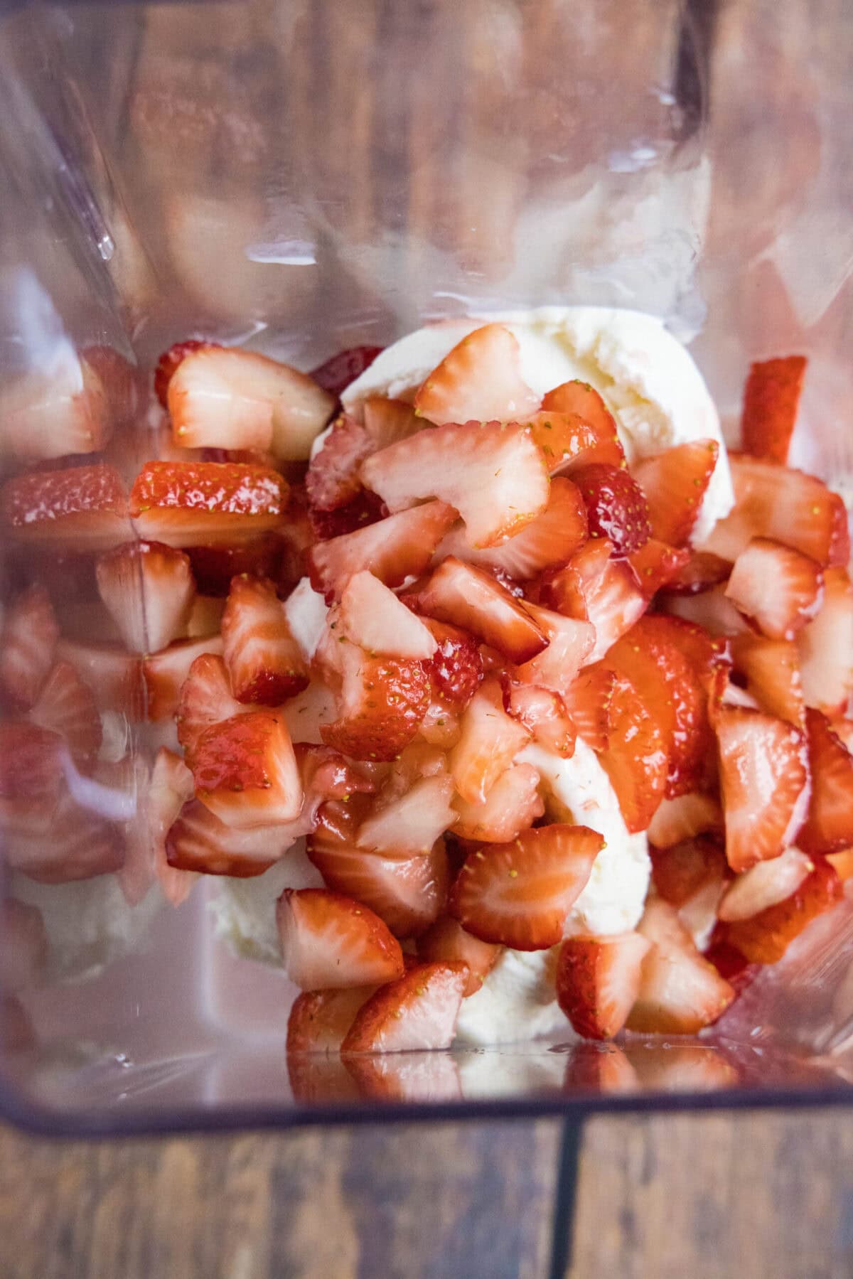 Overhead view of a blender filled with ice cream, milk, and strawberries