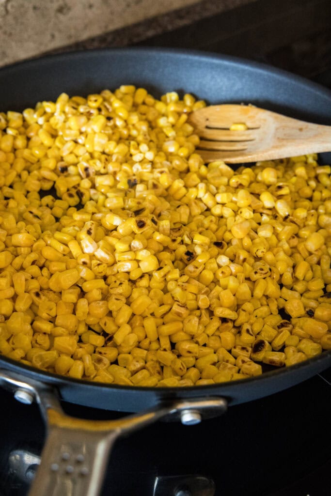 Sweet corn kernels cooking in a skillet.