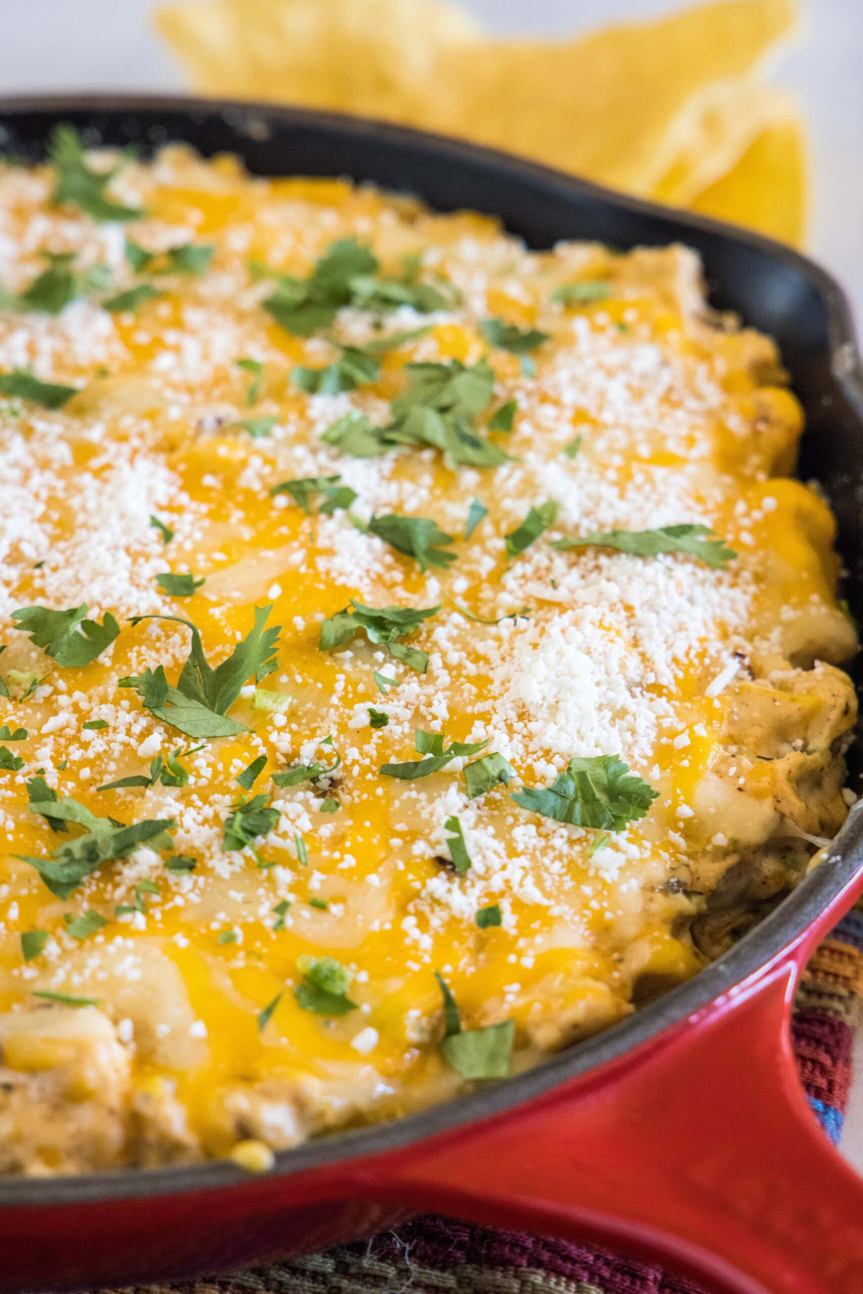 Baked street corn dip in a red skillet.
