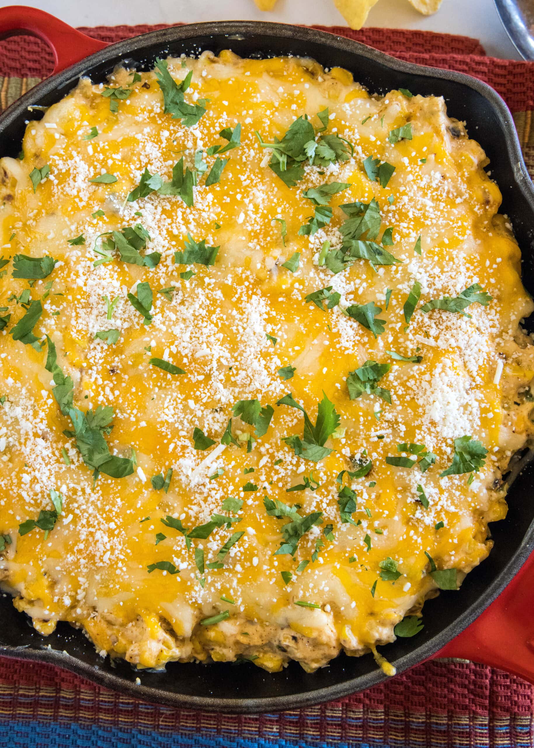 Overhead view of baked street corn dip in a red skillet.