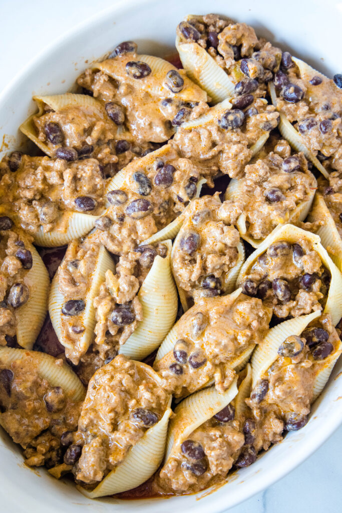 Taco stuffed shells assembled in a baking dish.