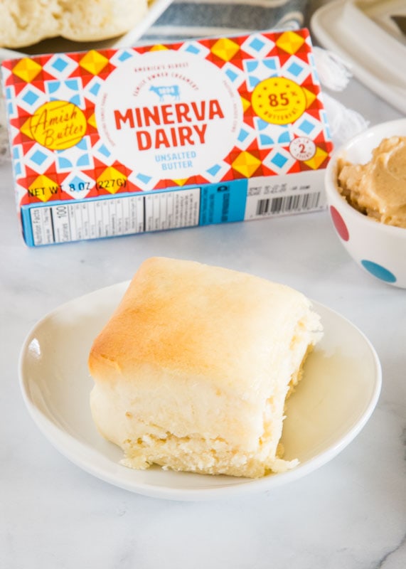 baked roll on white plate with bowl of cinnamon honey butter next to it