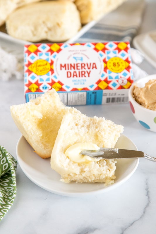 roll cut in half with butter being spread on it