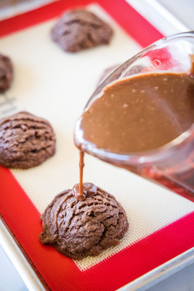 pouring chocolate frosting over cookies