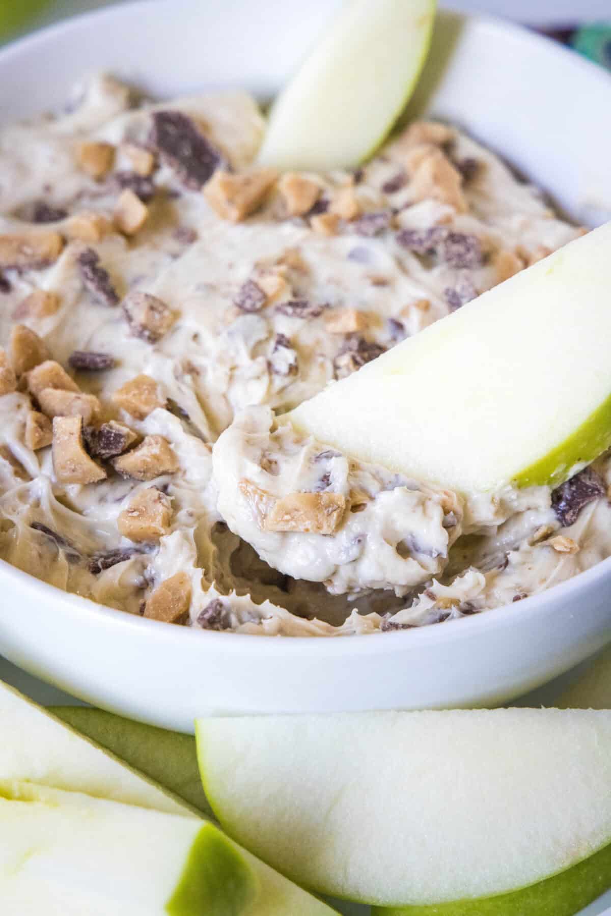 apple scooping up toffee apple dip from a bowl
