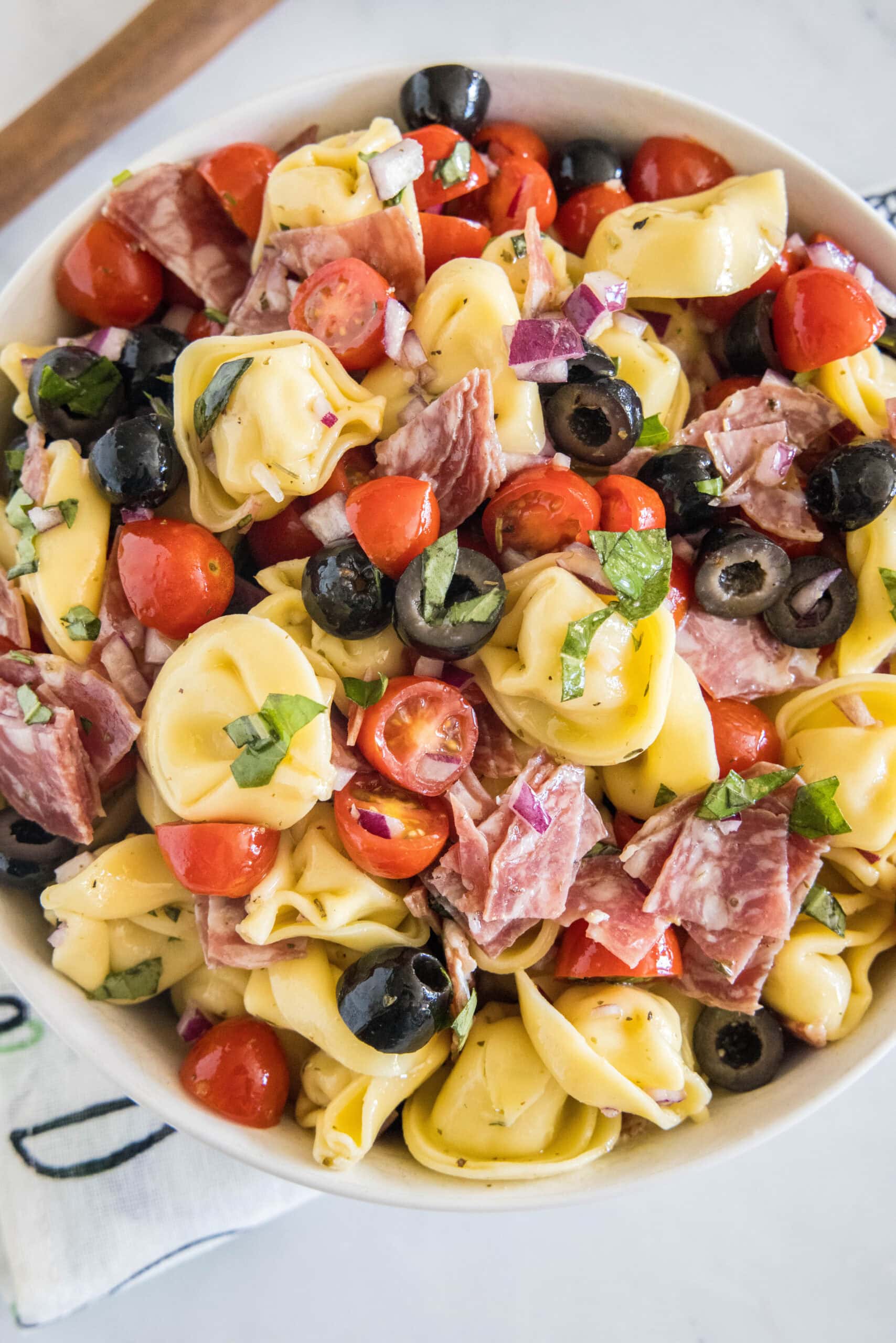 Overhead view of tortellini pasta salad in a white bowl.