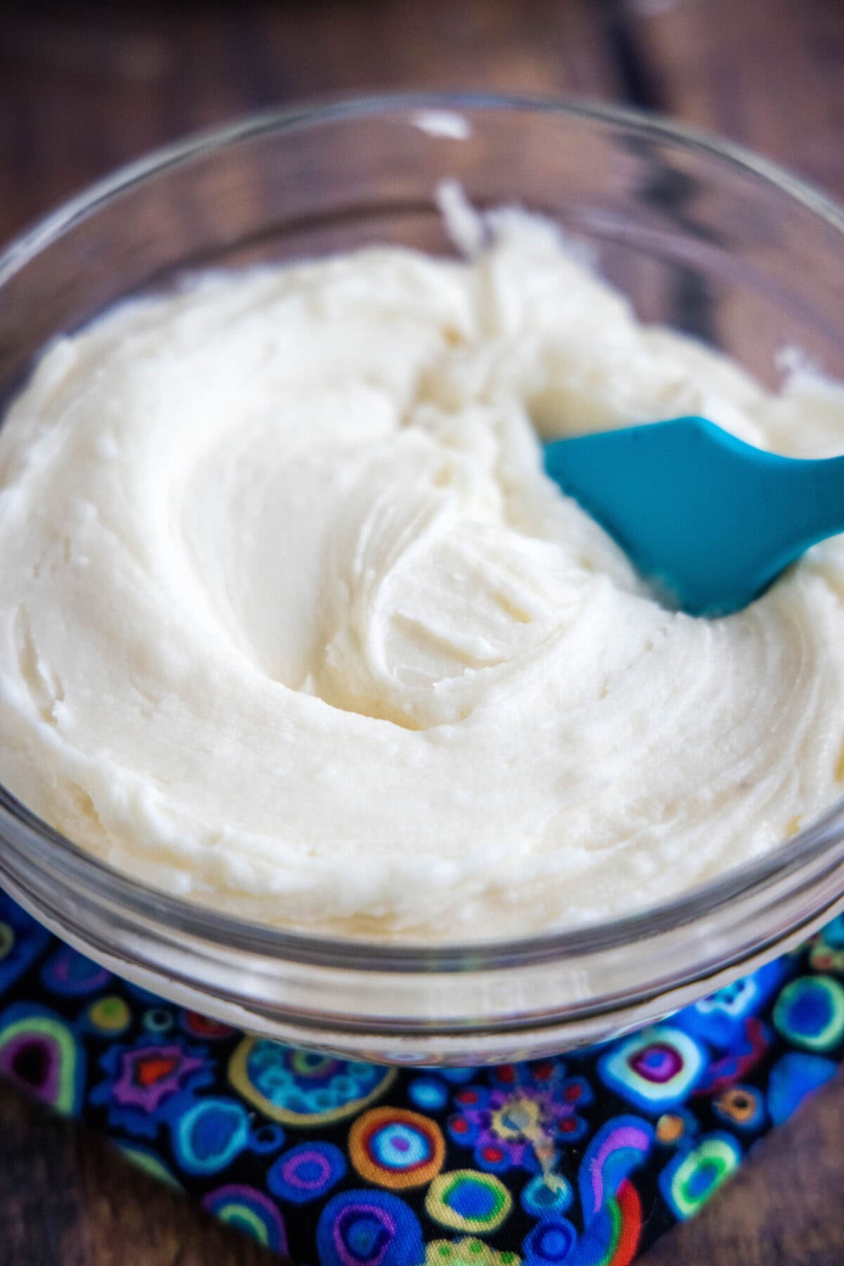 A bowl of vanilla frosting with a spatula in it