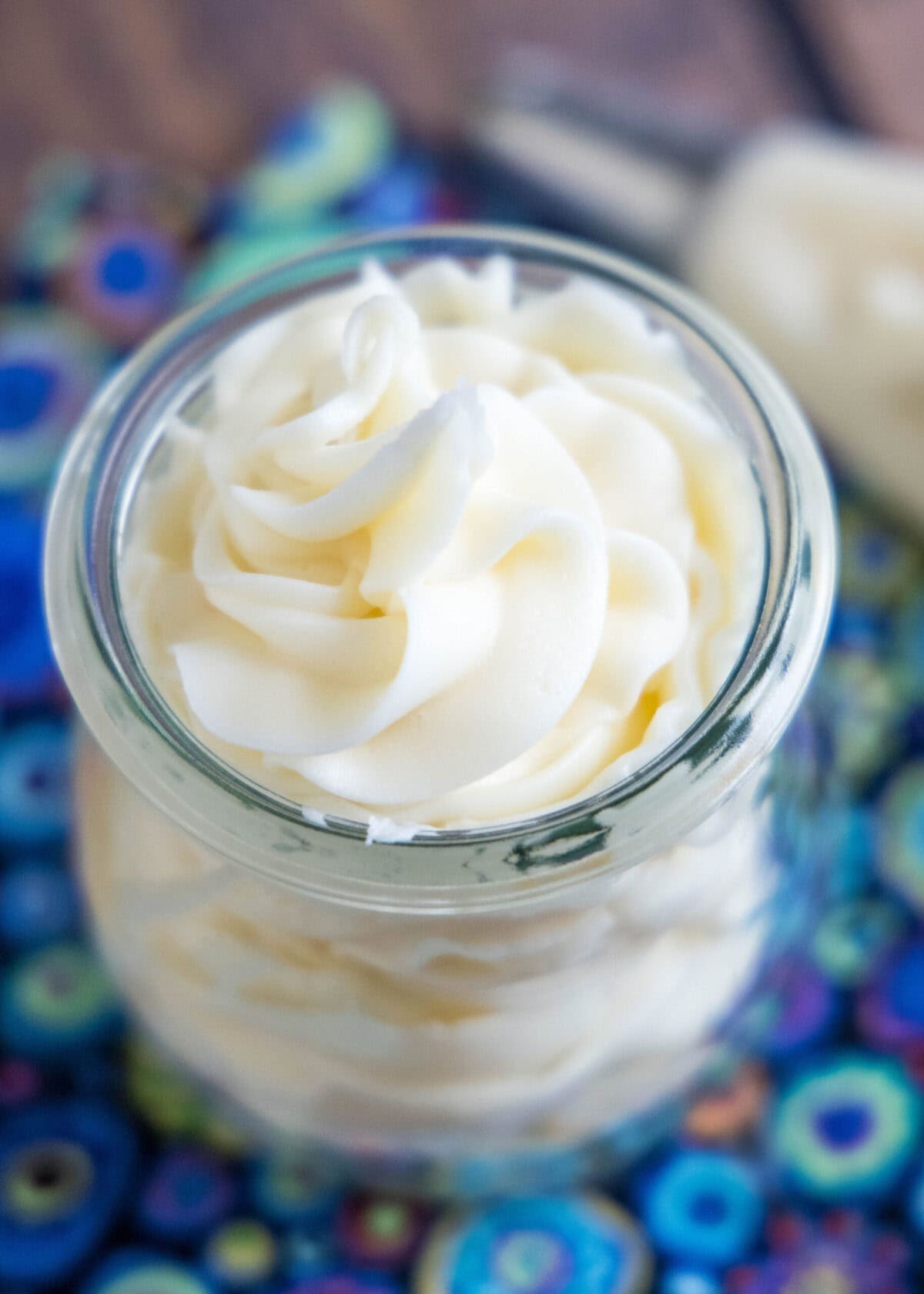 This 10-minute vanilla frosting recipe is creamy, rich, smooth, perfectly sweet, and the best frosting for spreading on homemade cakes. Close-up overhead view of a jar of vanilla frosting next to a piping back