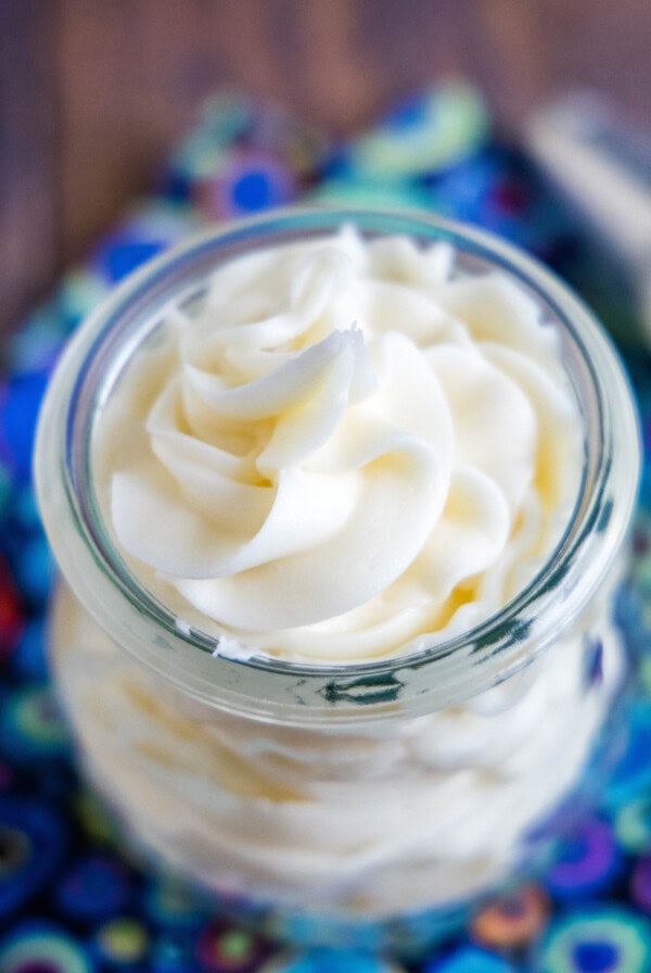 Overhead view of a jar of vanilla frosting next to a piping bag