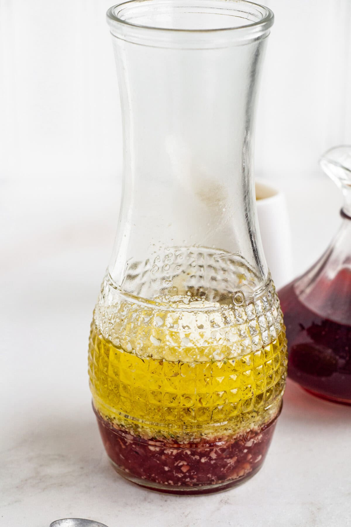 Red wine vinaigrette ingredients inside a glass carafe.
