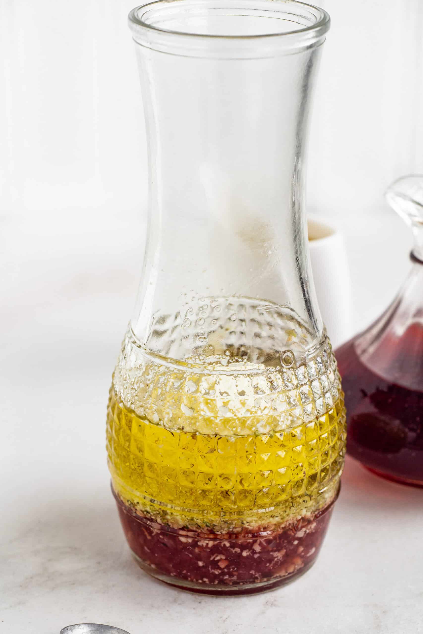 Red wine vinaigrette ingredients inside a glass carafe.