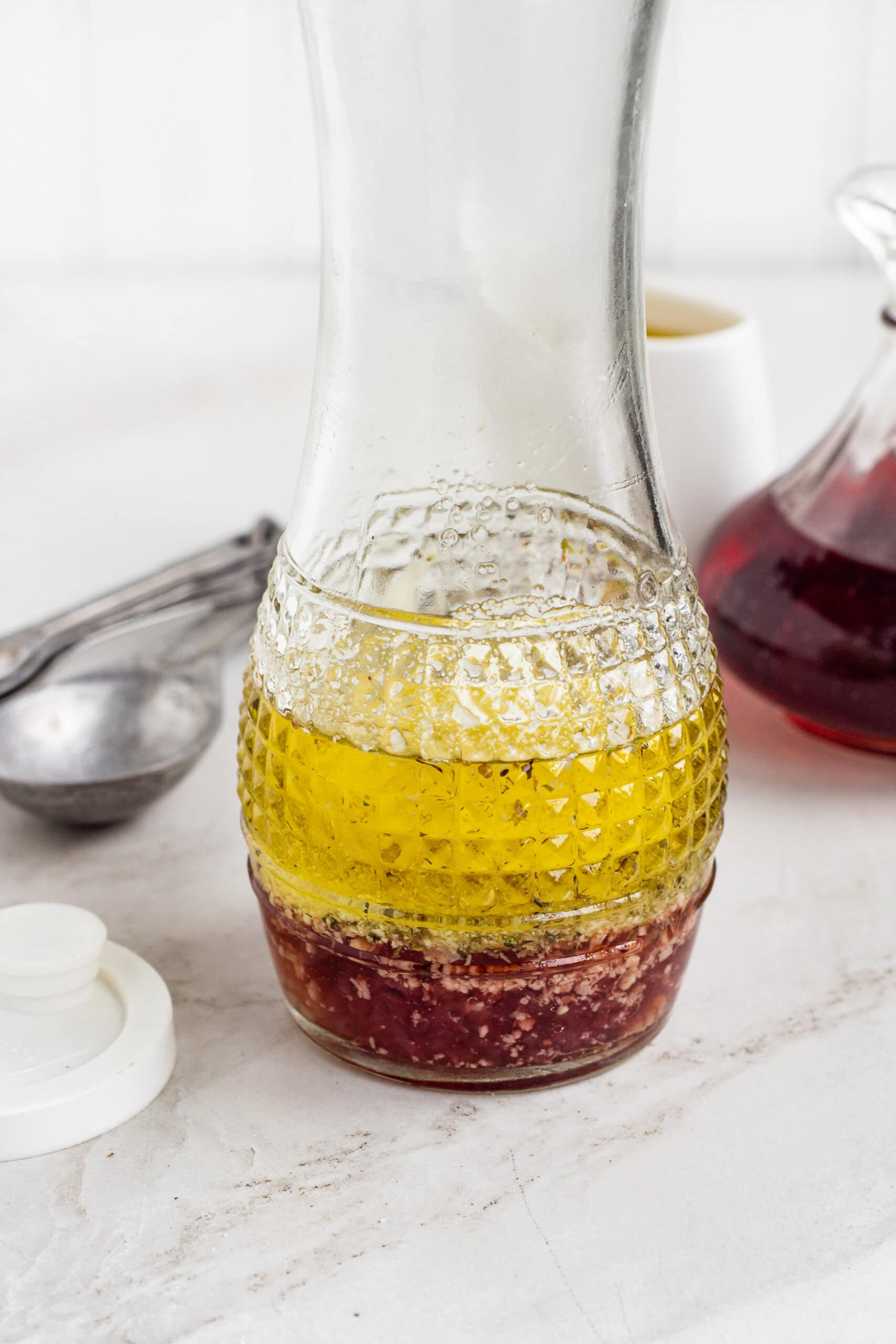 Red wine vinaigrette ingredients inside a glass carafe.