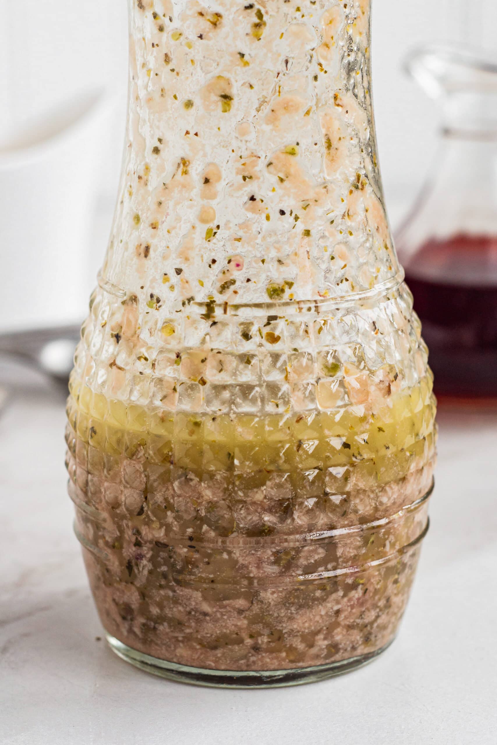 Emulsified red wine vinaigrette inside a glass carafe.