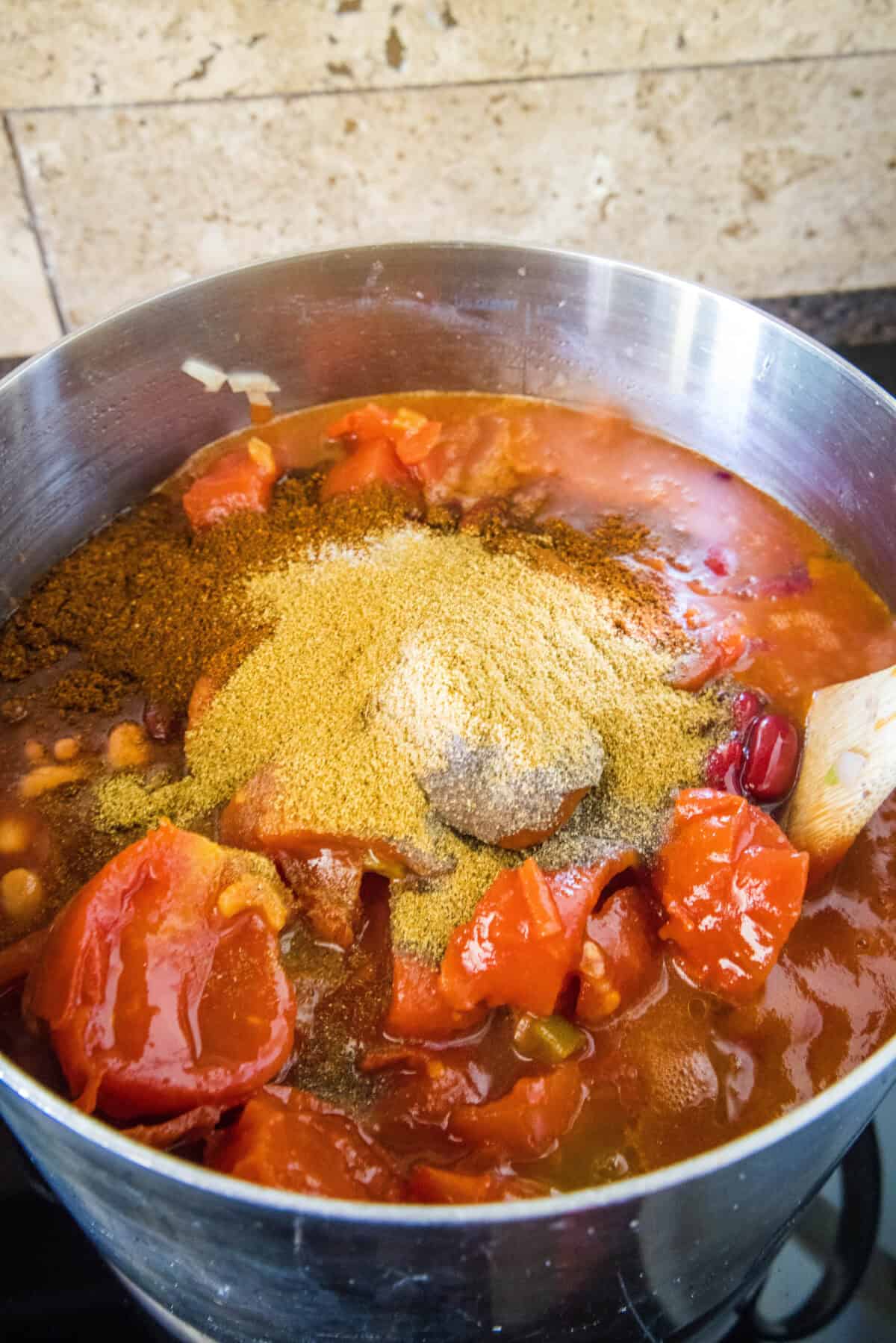 adding tomatoes and spices to a pot
