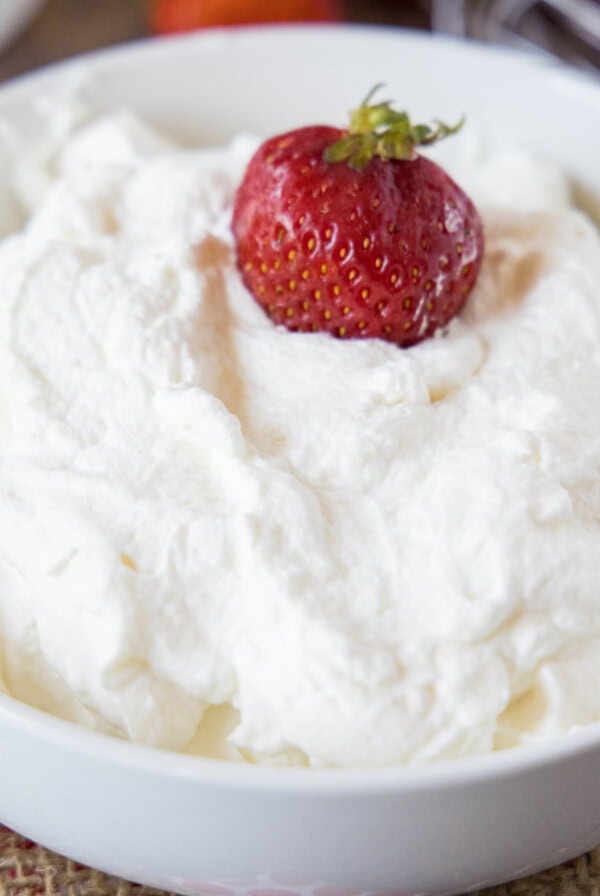 close up bowl of whipped cream with a strawberry in it